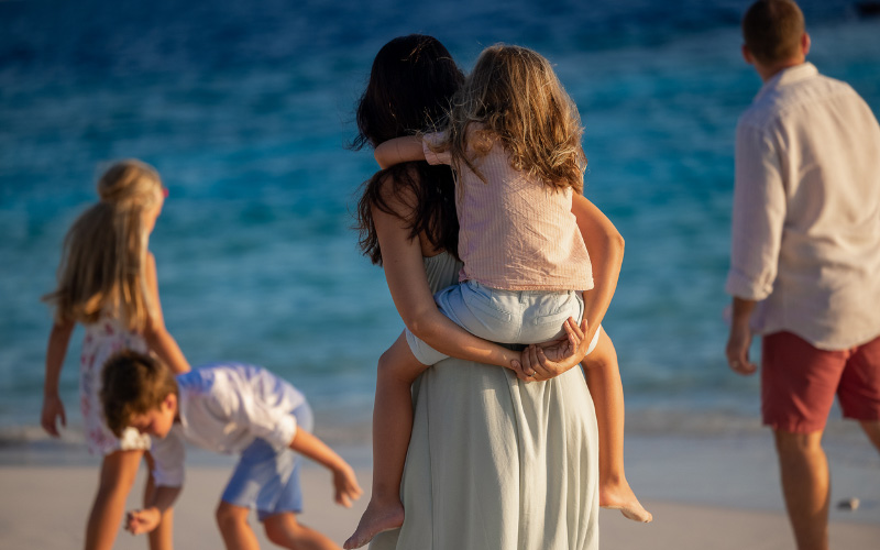A family walking along the beach at The Nautilus Maldives