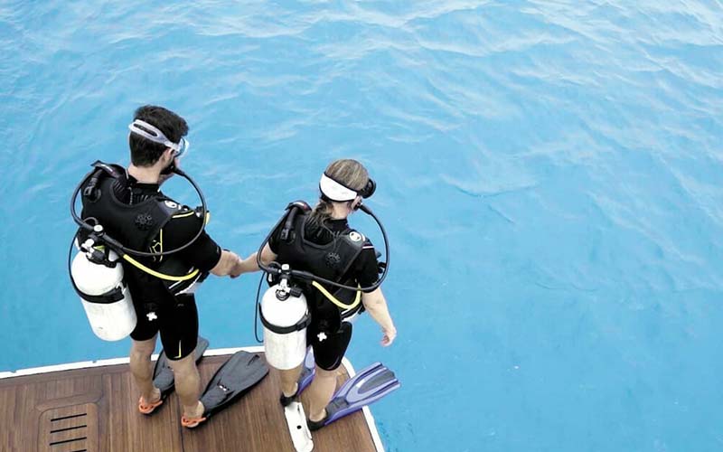 Two divers about to jump into the water from a boat