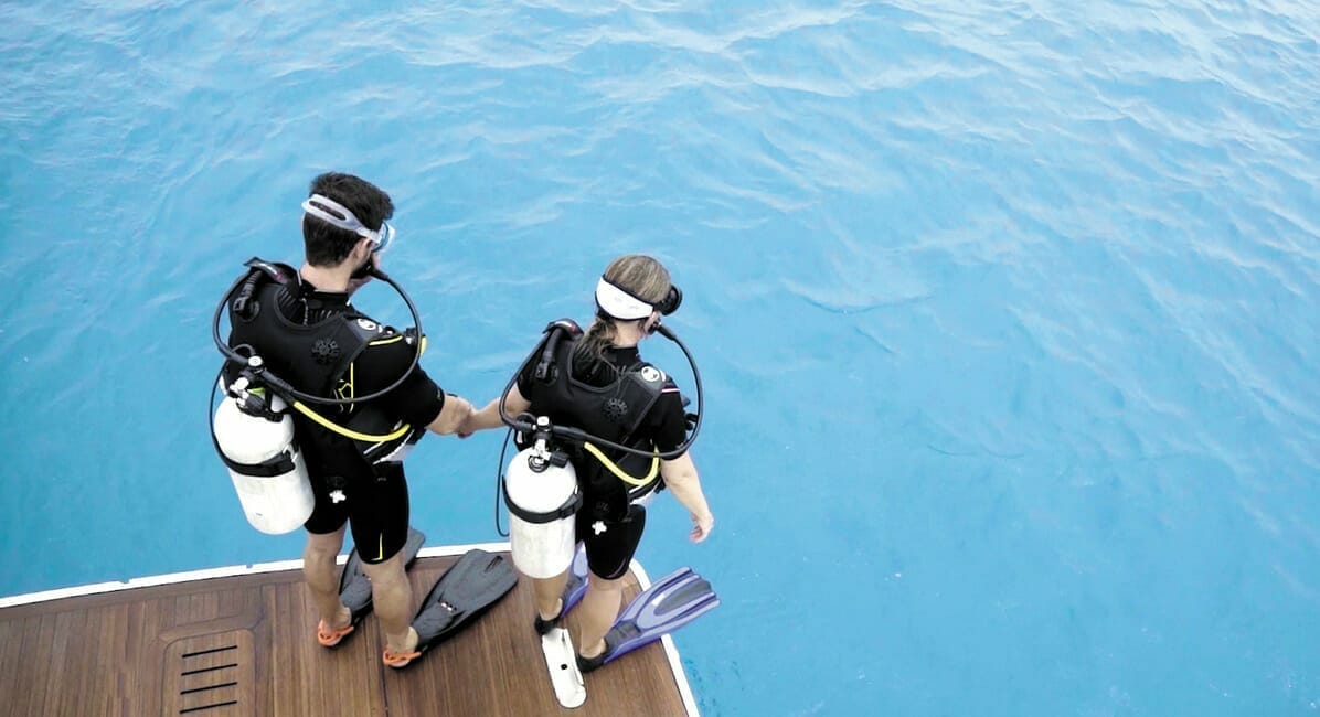 Two divers about to jump into the water from a boat