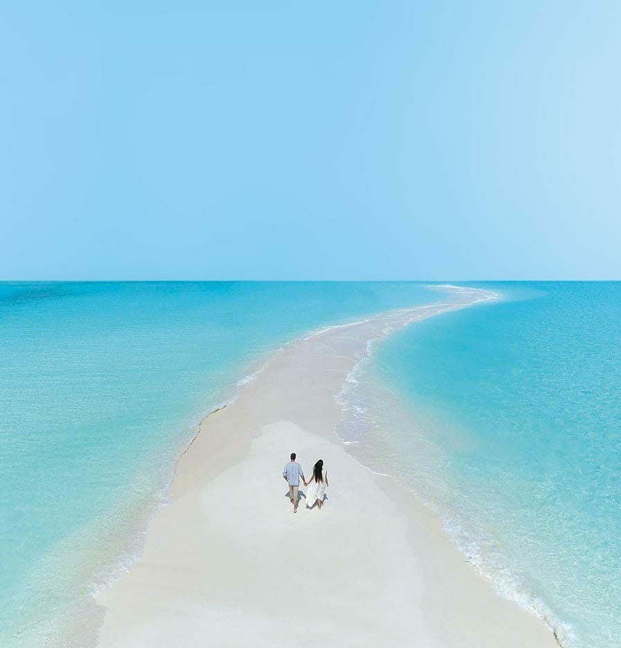 A couple holding hands and walking on a sandbank