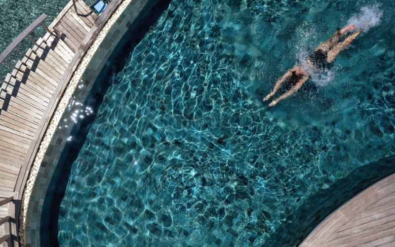 Woman jumping into the private pool of her ocean house at The Nautilus Maldives