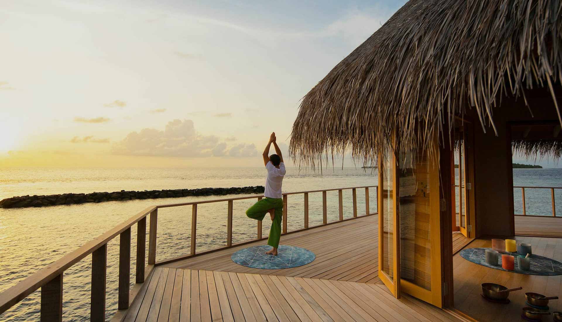 The Nautilus Maldives sunrise yoga — overwater spa pavilion with golden light over the Indian Ocean, Baa Atoll