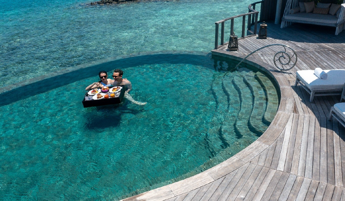 A couple enjoying a floating breakfast in the private pool of their ocean house at The Nautilus Maldives
