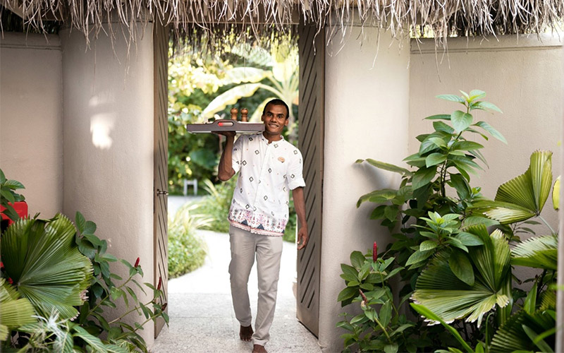 A personal butler walking with tray to provide room service at The Nautilus Maldives