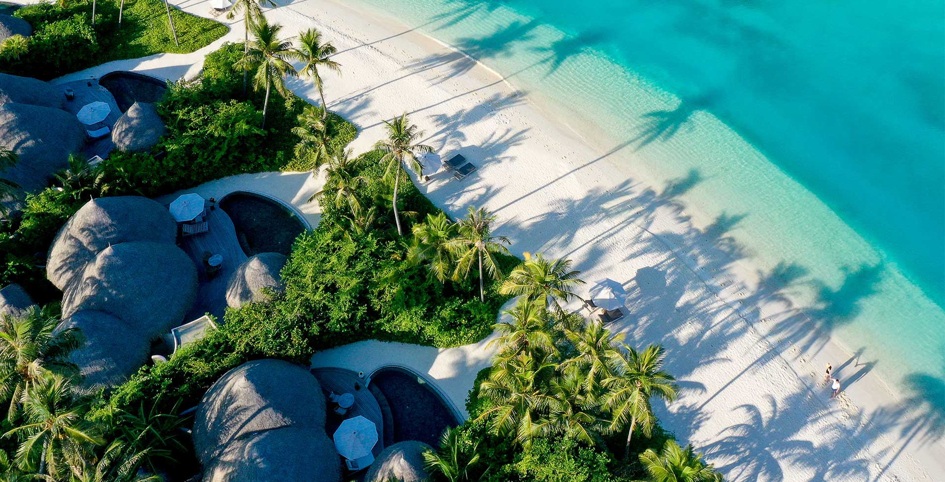 The Nautilus Maldives aerial — circular ocean houses and white sand curving into crystalline lagoon, Baa Atoll