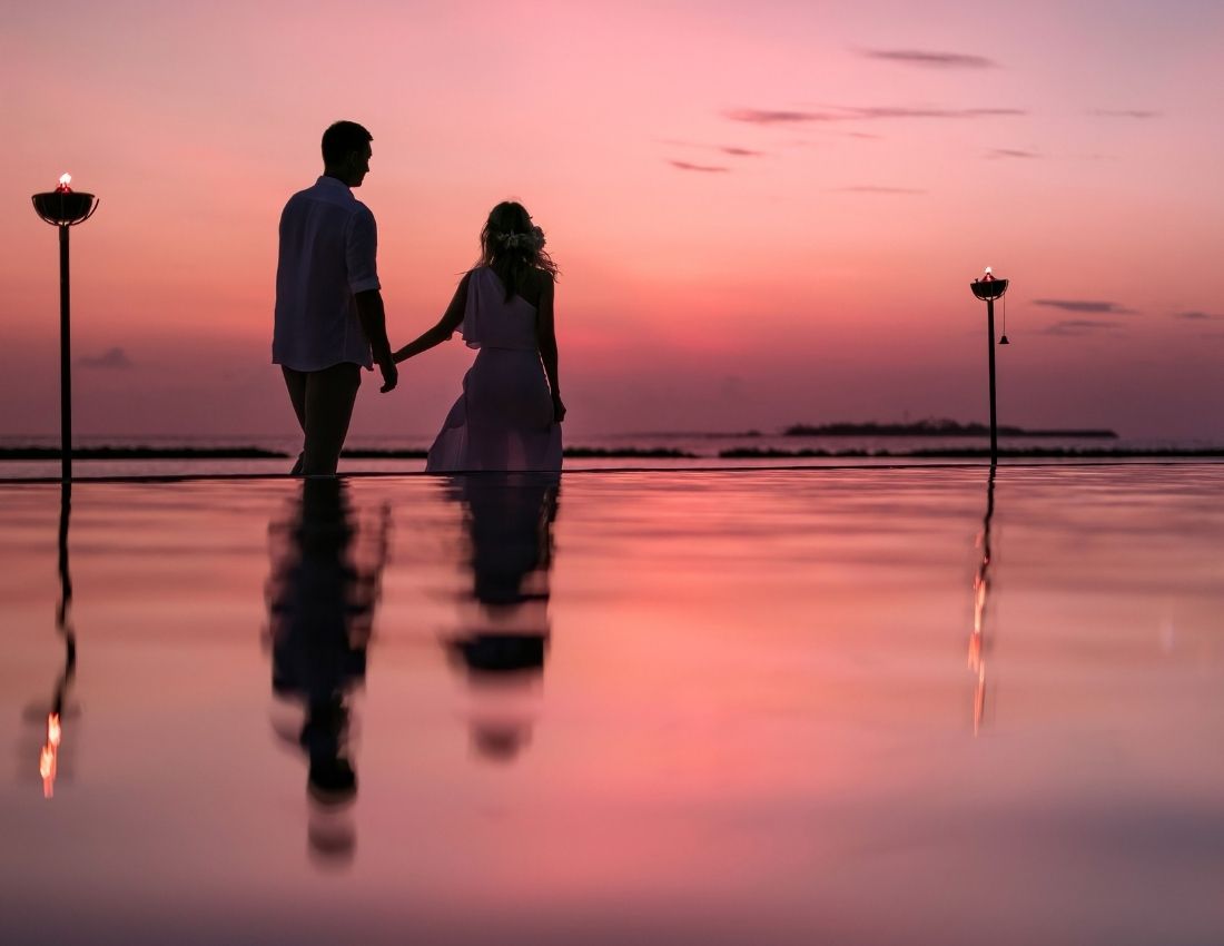 Couple holding hands and walking at sunset at The Nautilus Maldives