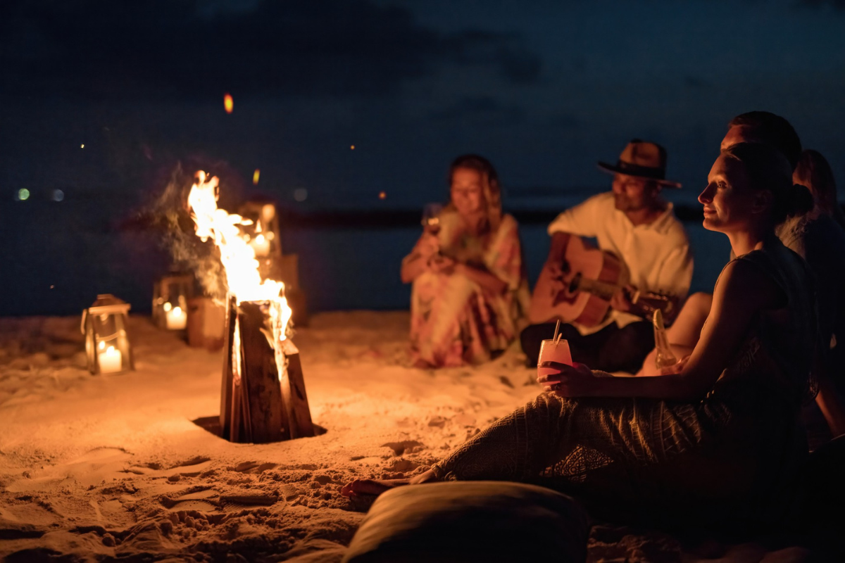 A group of friends around a bonfire on the beach at The Nautilus Maldives