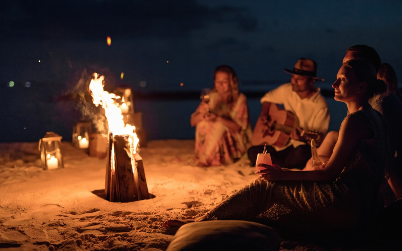 A group of friends around a bonfire on the beach at The Nautilus Maldives