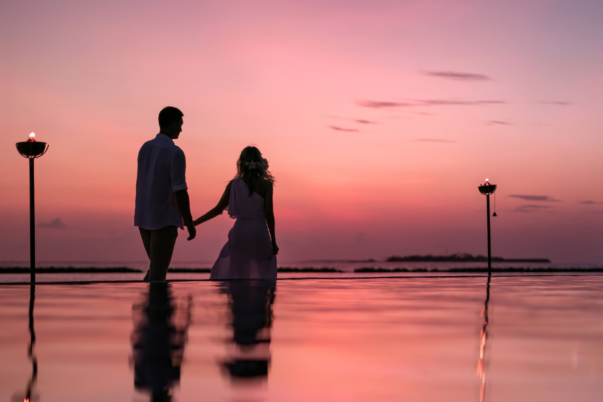 Couple holding hands and walking at sunset at The Nautilus Maldives