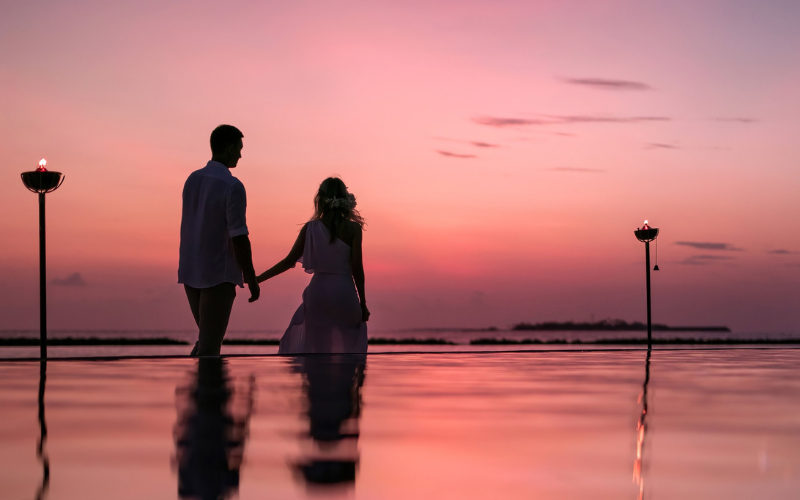 Couple holding hands and walking at sunset at The Nautilus Maldives