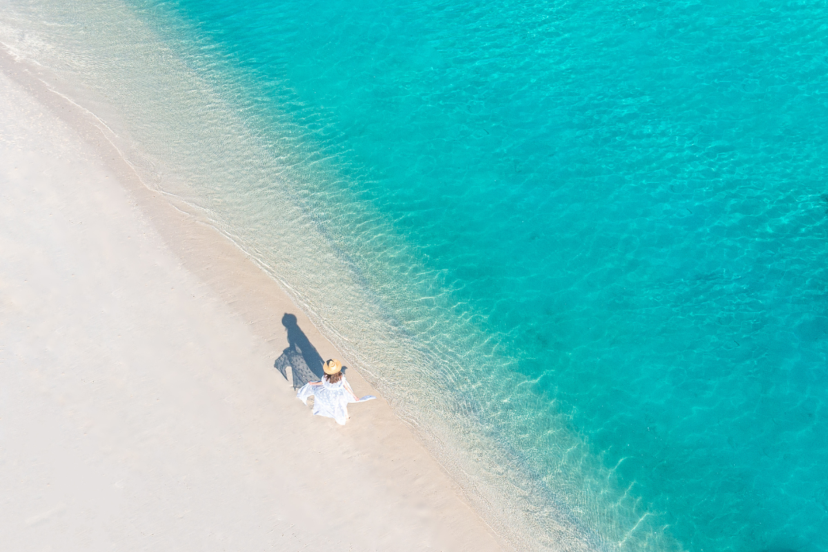 A woman walking on the powdery white beach at The Nautilus Maldives