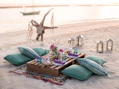 A luxurious bohemian picnic setup on the beach with cushions