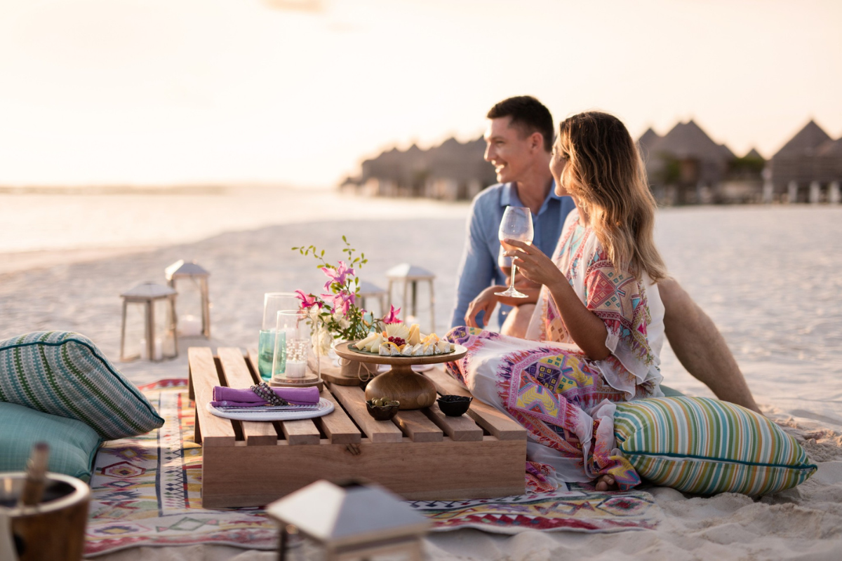 A couple having canapes and champagne on the beach at The Nautilus Maldives