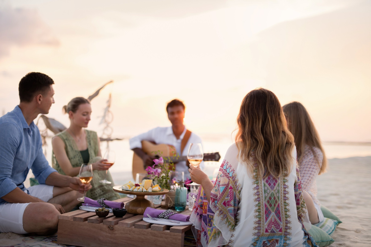 A group of friends sharing wine and canapes on the beach at The Nautilus Maldives
