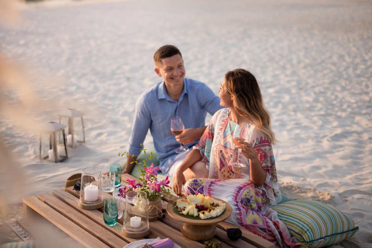 A couple enjoying wine and canapes on the beach at The Nautilus Maldives
