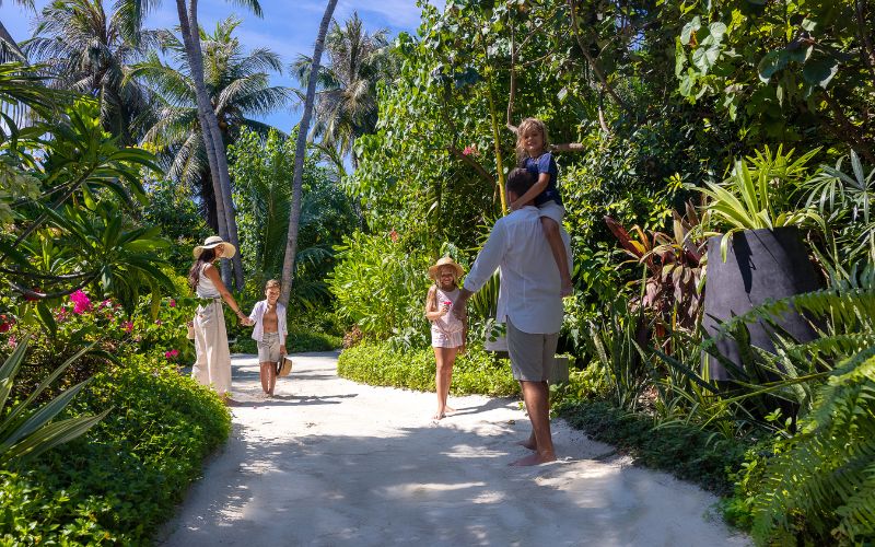 A family walking through the lush green island of The Nautilus Maldives