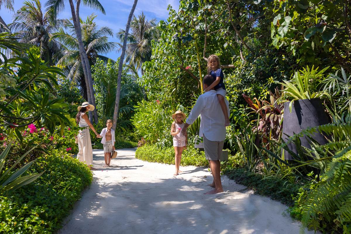 A family walking through the lush green island of The Nautilus Maldives