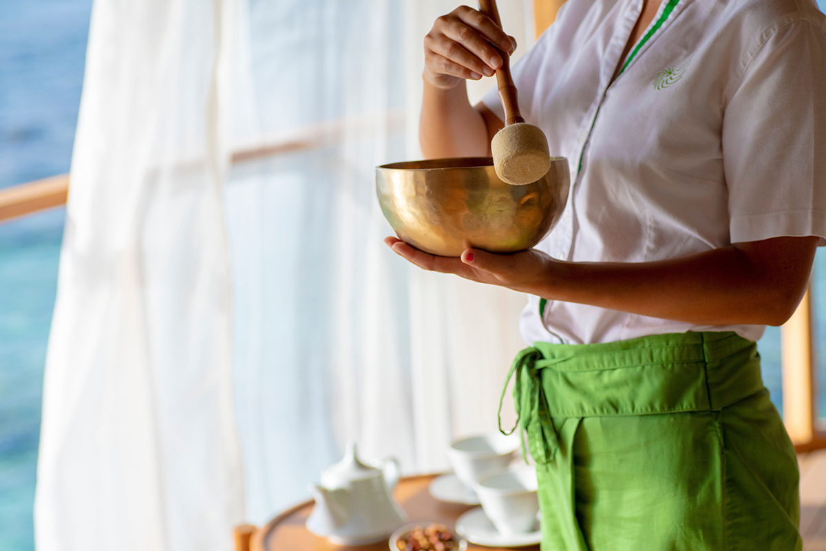 A spa therapist using a singing bowl