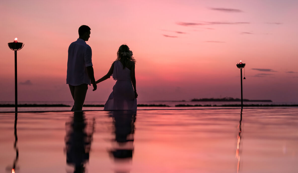 Couple holding hands and walking at sunset at The Nautilus Maldives