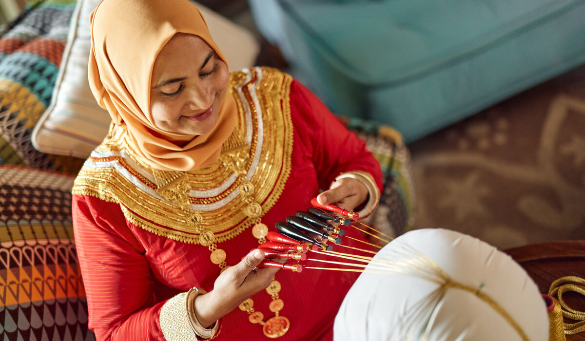A woman in traditional Maldivian clothing demonstrating a local craft
