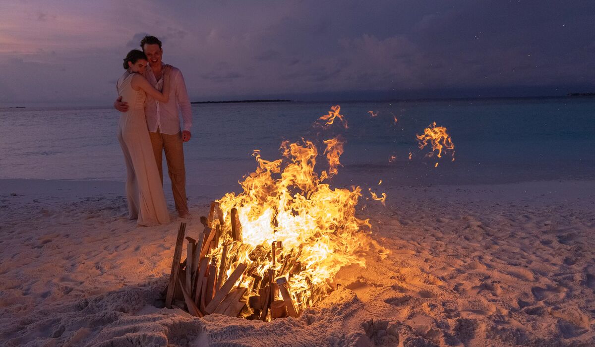A couple by a bonfire at a sandbank a short ride away from The Nautilus Maldives