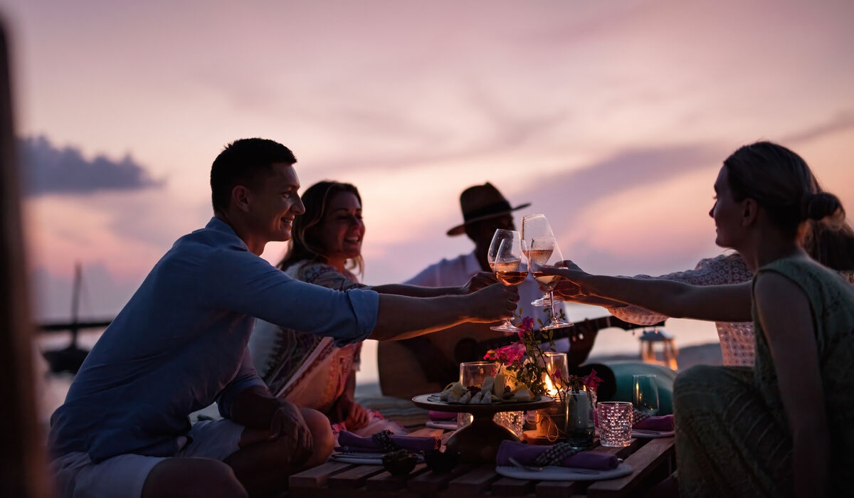 A group of friends toasting with champagne on the beach at The Nautilus Maldives
