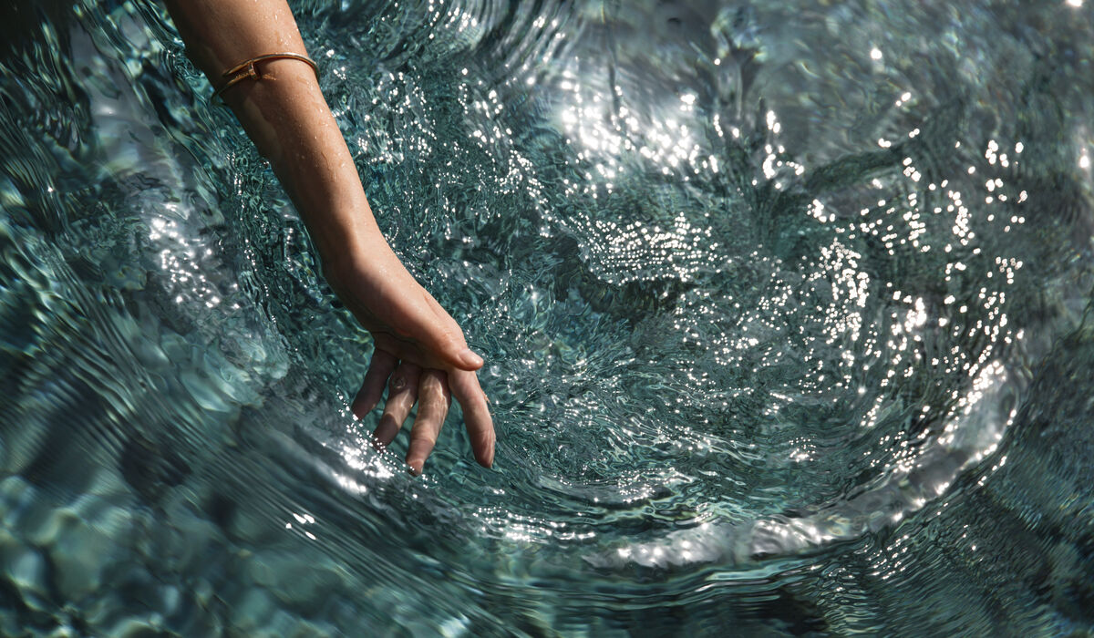 A woman dipping her hand into the water of her private pool at The Nautilus Maldives
