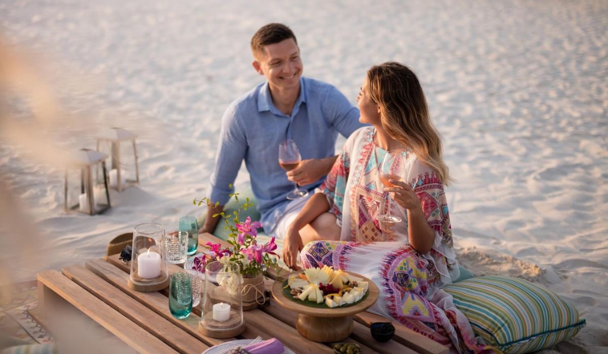 Couple enjoying champagne and canapes on the beach at The Nautilus Maldives