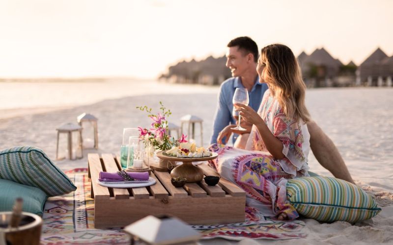 Couple having wine and canapes on the beach at The Nautilus Maldives