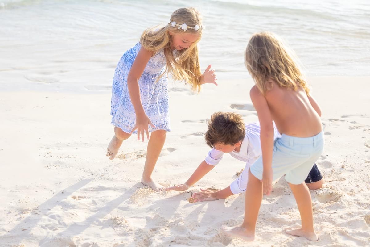 Children laughing and playing in the sand by the shoreline, enjoying a fun-filled day at the beach.