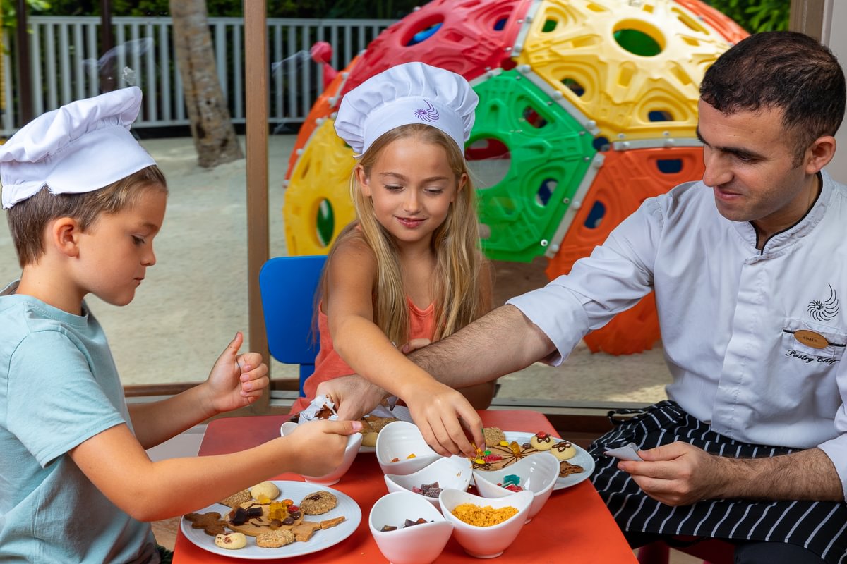 Children participating in a cookie decorating class with a chef, part of a fun activity at a resort's kids' club.